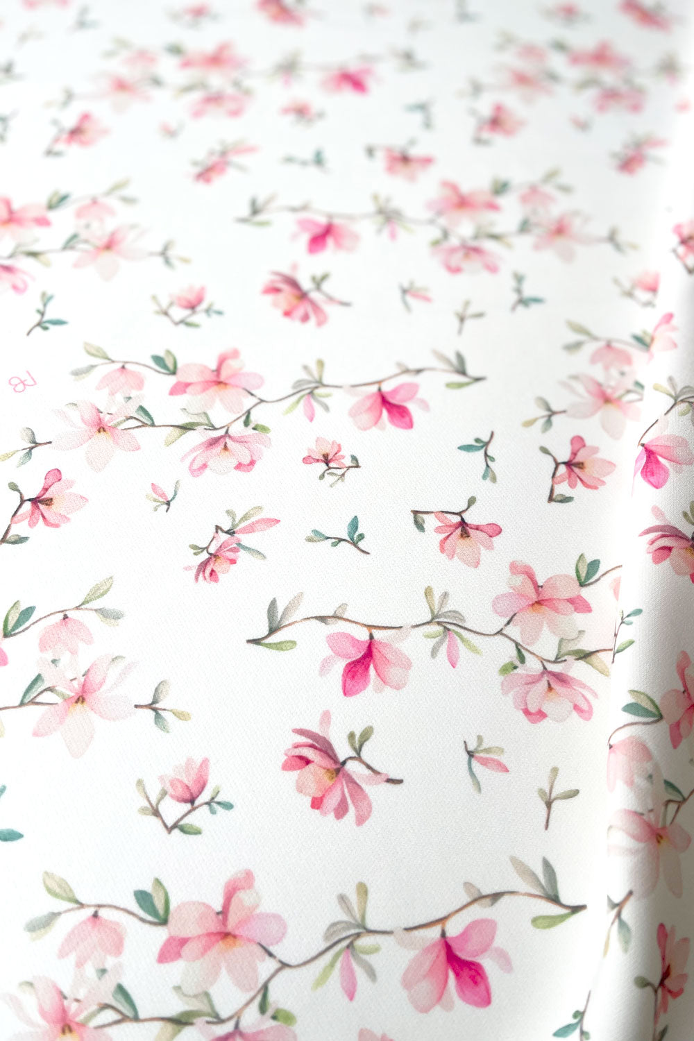 מפת שולחן גבריאלה מעוטרת בפרחים ורודים עדינים על רקע שמנת