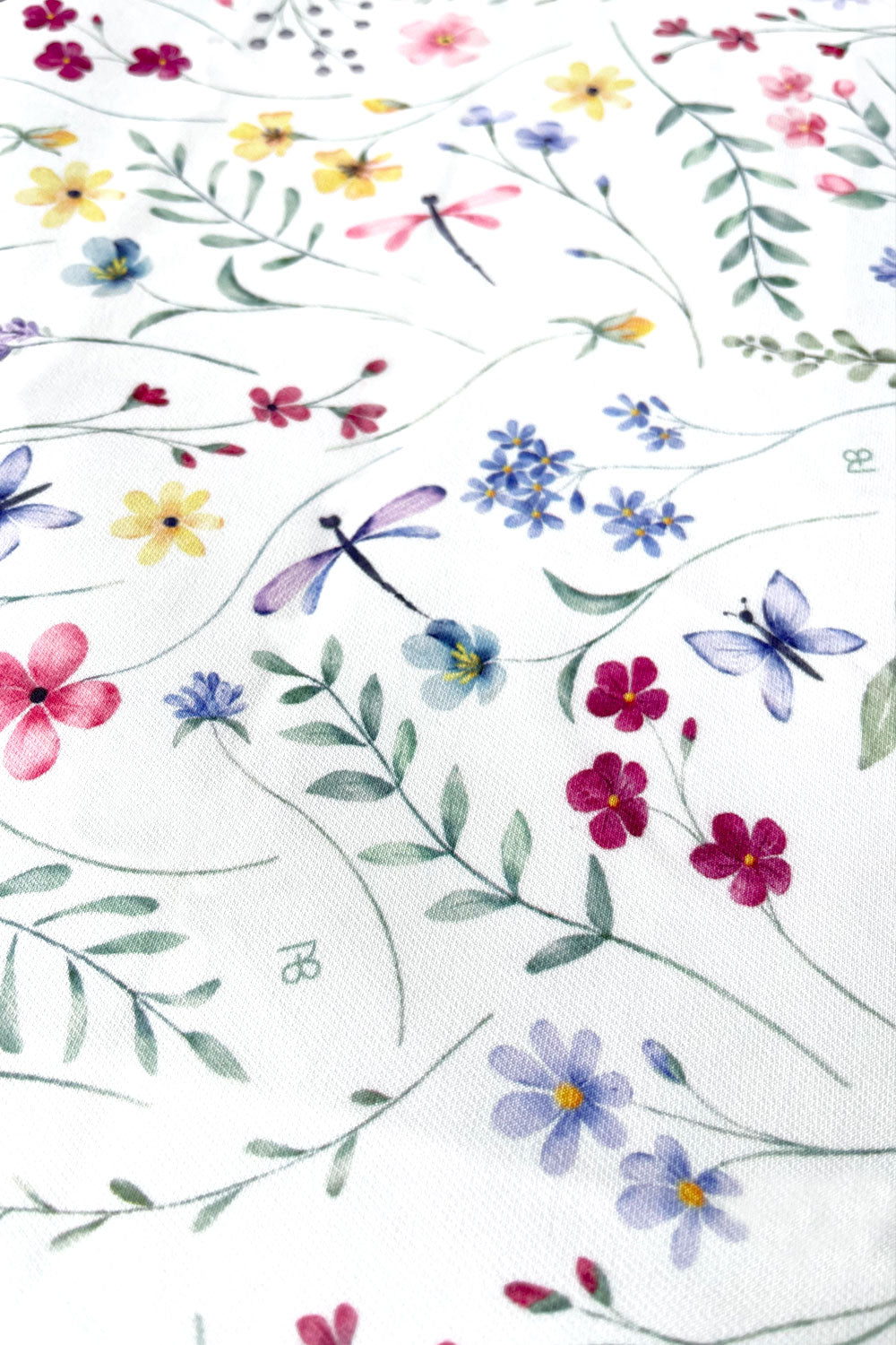 תקריב על בד מפת שולחן נוי עם פרחים ורודים וירוקים רכים