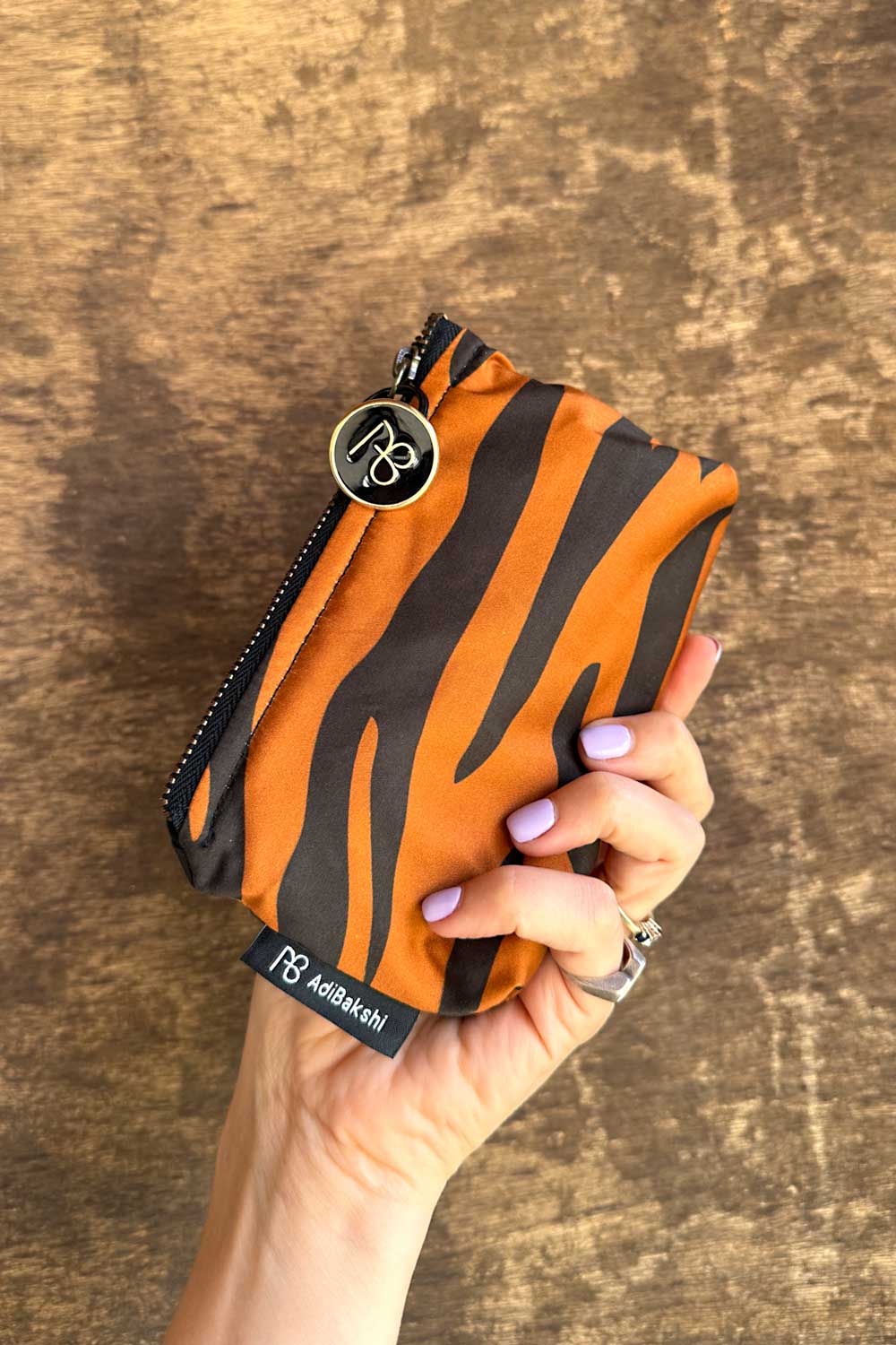 ארנק רותם על רקע עץ – הדגשת טקסטורת הנמר והגוון החם