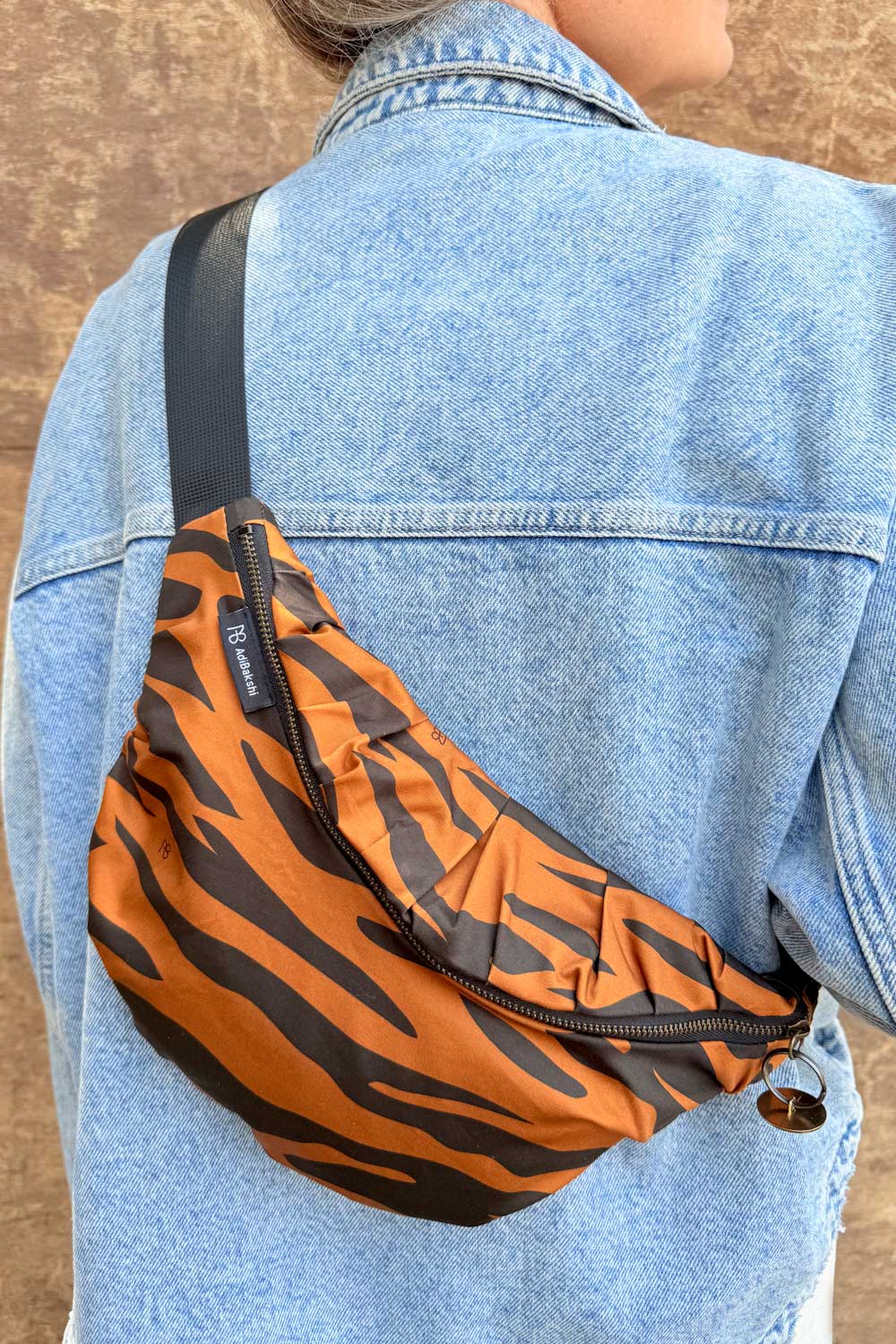 מבט גב של הפאוץ' המדגיש את צורתו הקמורה והרצועה השחורה המתכווננת